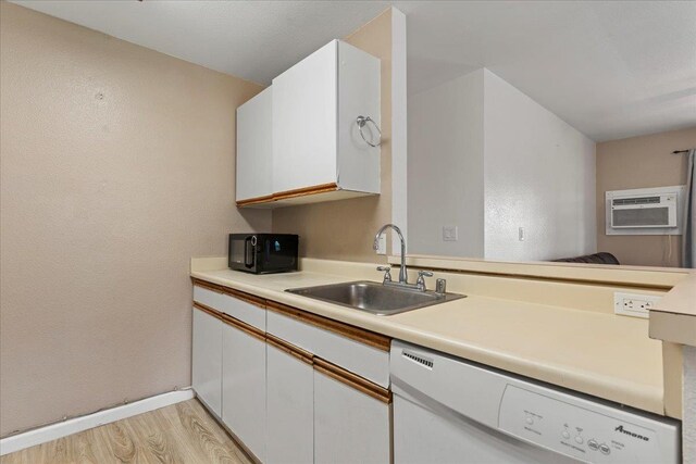 kitchen with white dishwasher, sink, a wall mounted air conditioner, and white cabinets