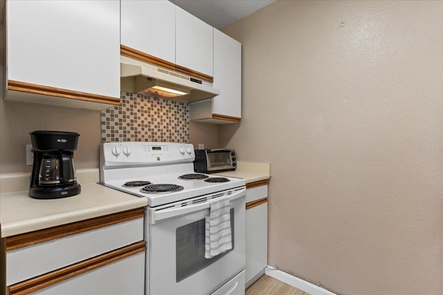 kitchen with white electric range oven, tasteful backsplash, light countertops, under cabinet range hood, and white cabinetry