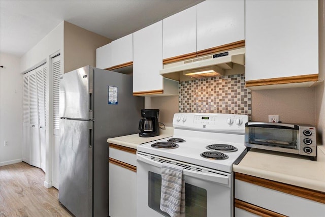 kitchen with under cabinet range hood, light countertops, freestanding refrigerator, decorative backsplash, and white range with electric stovetop