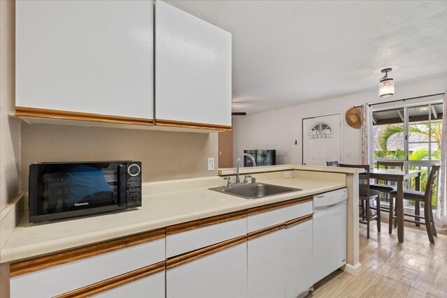 kitchen featuring white dishwasher, sink, light hardwood / wood-style flooring, and white cabinets