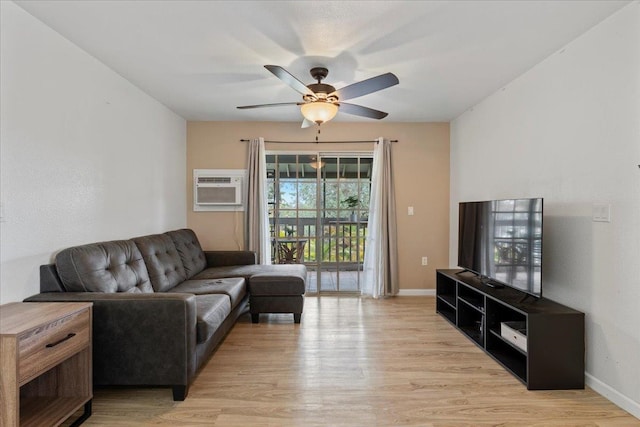 living room with a wall mounted AC, light hardwood / wood-style floors, and ceiling fan