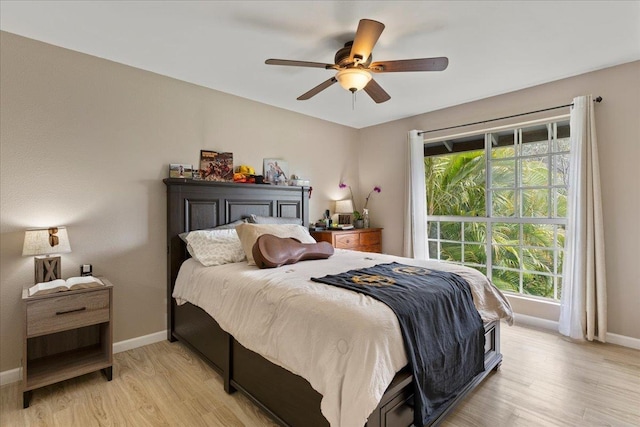 bedroom with light wood-style floors, ceiling fan, and baseboards