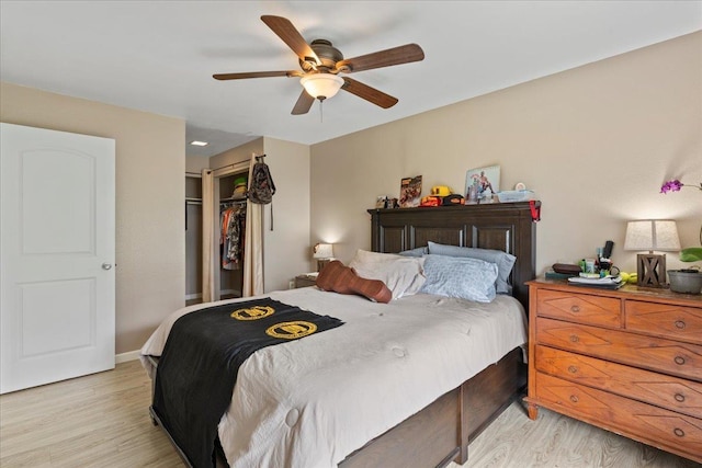 bedroom with light wood-style flooring, baseboards, ceiling fan, and a closet