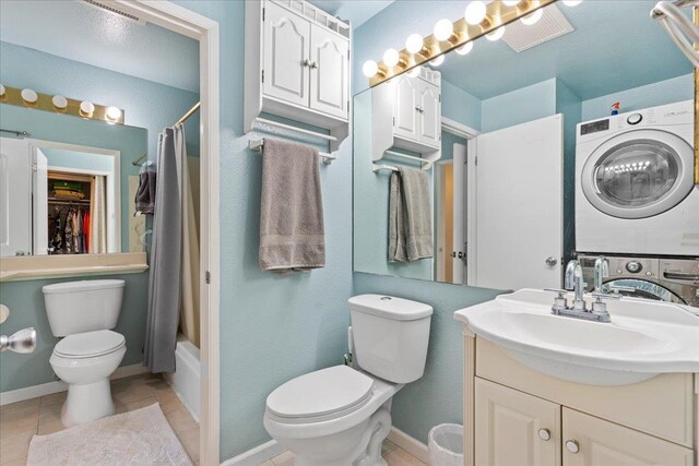 full bathroom featuring stacked washing maching and dryer, shower / bath combination with curtain, tile patterned flooring, vanity, and toilet