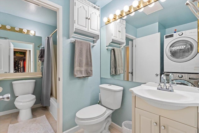 full bathroom featuring toilet, stacked washer / dryer, vanity, tile patterned flooring, and baseboards
