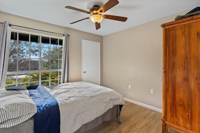 bedroom featuring light wood-style floors, baseboards, and a ceiling fan