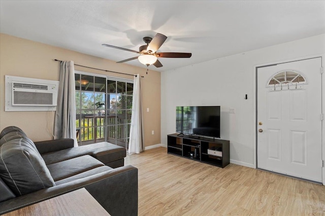 living room with a wall mounted AC, light hardwood / wood-style floors, and ceiling fan