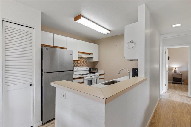 kitchen featuring sink, stainless steel fridge, white cabinetry, white electric range oven, and kitchen peninsula