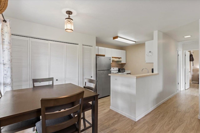 kitchen with range with electric stovetop, light wood finished floors, freestanding refrigerator, under cabinet range hood, and baseboards