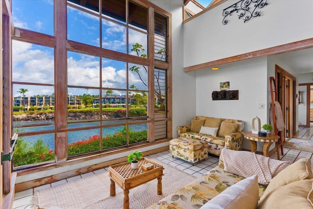 living room featuring a towering ceiling, a water view, and light tile patterned flooring