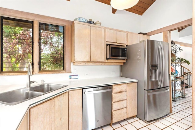 kitchen with light brown cabinets, vaulted ceiling, sink, light tile patterned floors, and stainless steel appliances