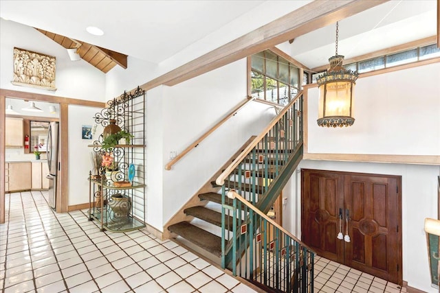 stairs with a chandelier, tile patterned flooring, and lofted ceiling