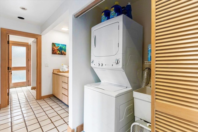 laundry area with sink, stacked washing maching and dryer, and light tile patterned floors