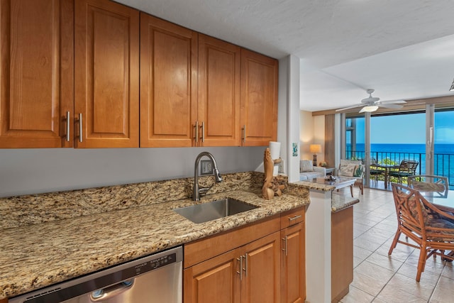 kitchen featuring light stone countertops, sink, a water view, ceiling fan, and stainless steel dishwasher