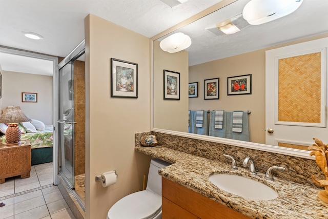 bathroom featuring tile patterned flooring, vanity, toilet, and a shower with shower door