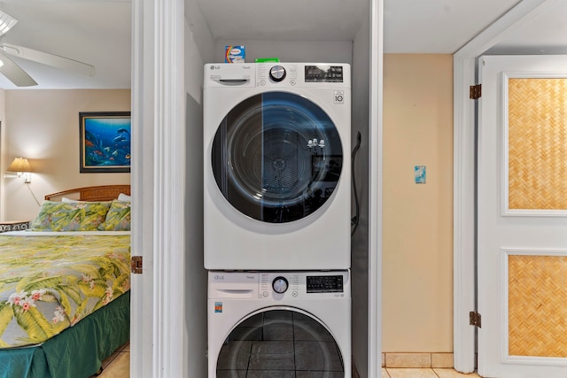 laundry area featuring stacked washer and clothes dryer, ceiling fan, and tile patterned floors