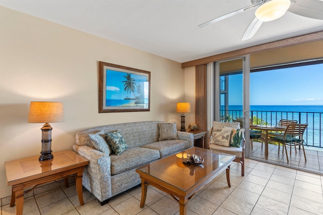 living room featuring ceiling fan, light tile patterned floors, and a water view