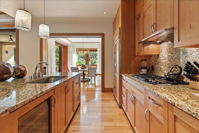 kitchen with light stone counters, extractor fan, sink, pendant lighting, and wine cooler