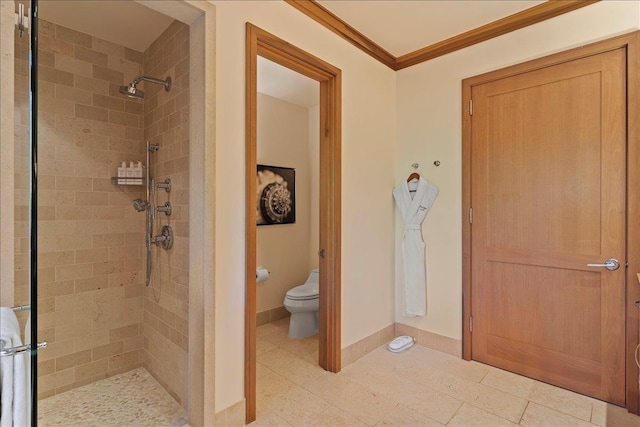 bathroom with tiled shower, toilet, and crown molding