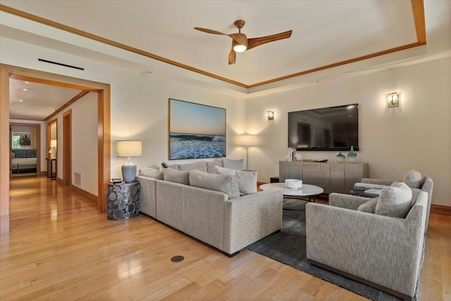 living room with ceiling fan, light wood-type flooring, and crown molding