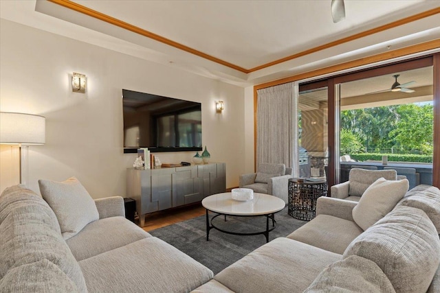 living room with ceiling fan, wood-type flooring, crown molding, and a tray ceiling