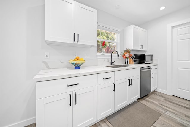 kitchen with sink, white cabinets, stainless steel appliances, light stone countertops, and light wood-type flooring