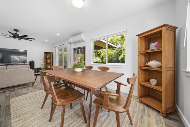 dining room featuring ceiling fan, a wall mounted air conditioner, and light wood-type flooring