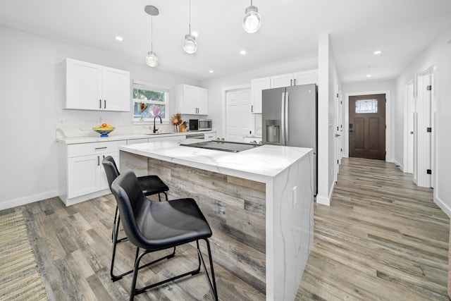 kitchen featuring white cabinetry, a kitchen island, sink, and light stone counters