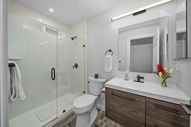 bathroom featuring a shower with door, vanity, hardwood / wood-style floors, and toilet