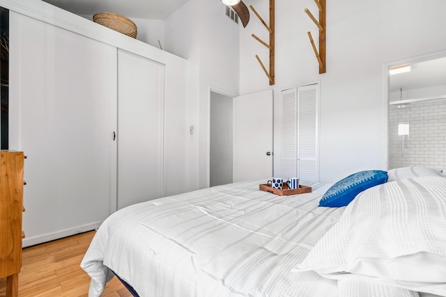 bedroom with hardwood / wood-style floors, ensuite bath, and a high ceiling