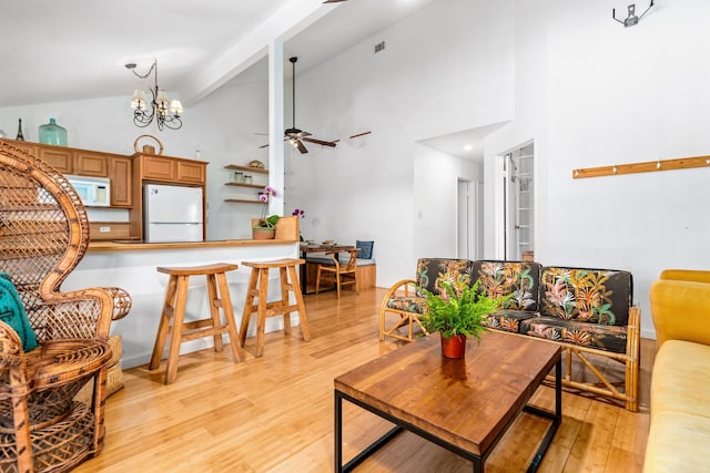 living room featuring ceiling fan with notable chandelier, light hardwood / wood-style floors, and high vaulted ceiling