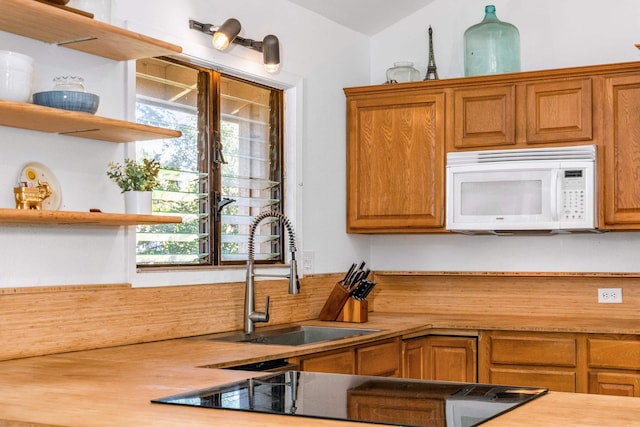 kitchen featuring butcher block countertops, sink, and lofted ceiling