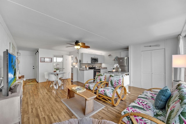 living room with ceiling fan and light wood-type flooring