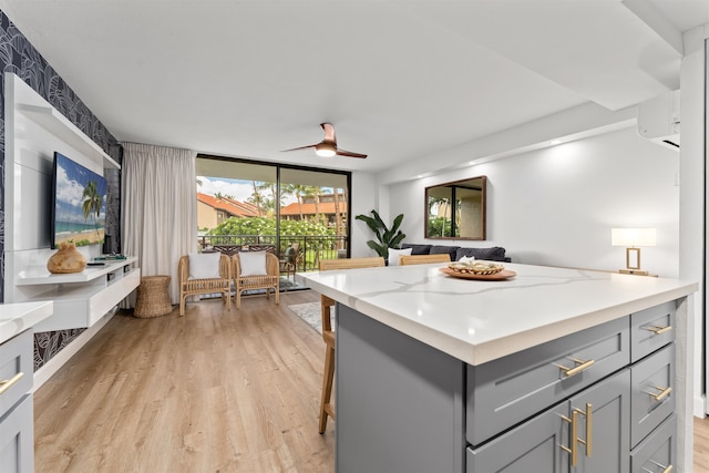 kitchen featuring gray cabinetry, light stone countertops, ceiling fan, and light wood-type flooring