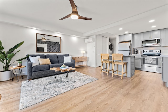 living room featuring light hardwood / wood-style flooring, ceiling fan, and a wall mounted AC