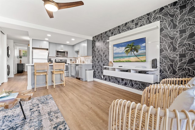 living room featuring sink, light hardwood / wood-style floors, and ceiling fan