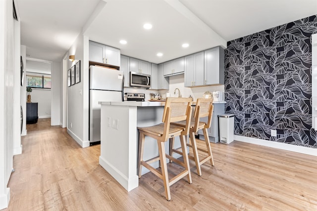 kitchen with kitchen peninsula, light hardwood / wood-style floors, white fridge, and gray cabinetry