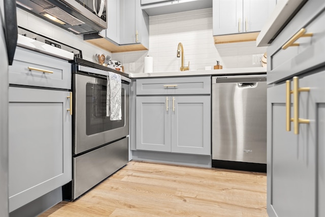 kitchen with appliances with stainless steel finishes, tasteful backsplash, and light wood-type flooring