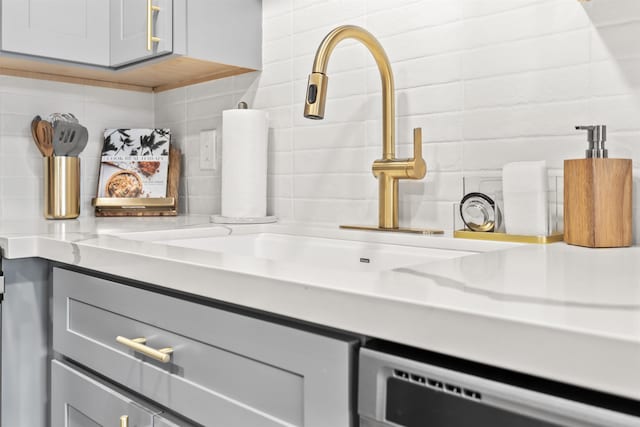 details featuring tasteful backsplash, vanity, and stainless steel dishwasher