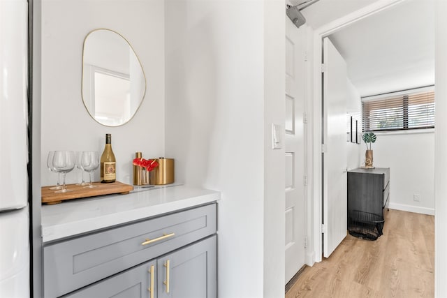 interior space featuring white refrigerator, gray cabinetry, and light wood-type flooring