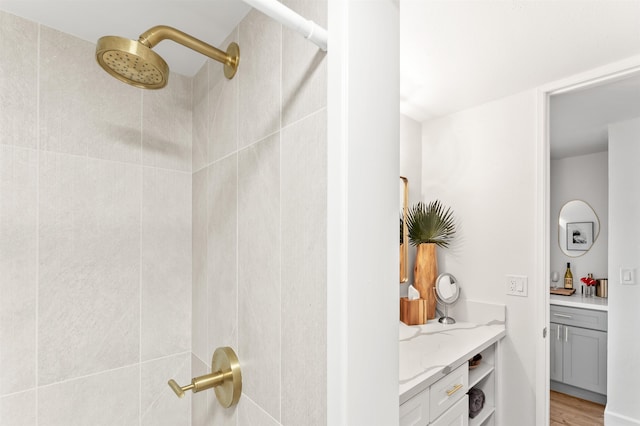 interior details featuring light hardwood / wood-style flooring, tiled shower, and vanity