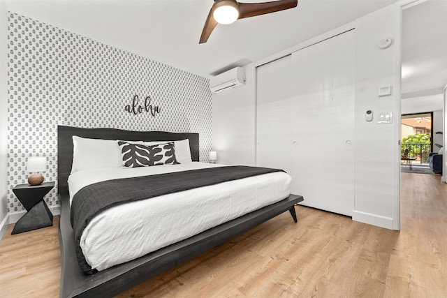 bedroom featuring light hardwood / wood-style flooring, ceiling fan, and a wall mounted AC