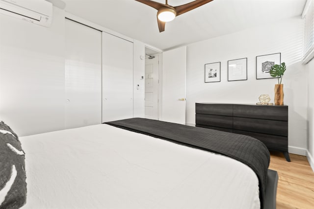 bedroom with an AC wall unit, a closet, ceiling fan, and light wood-type flooring