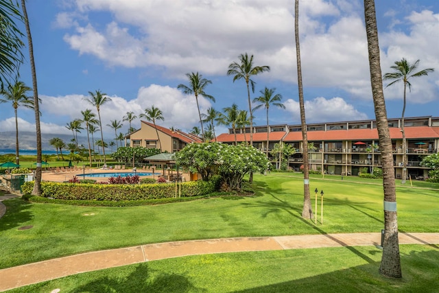 view of property's community with a pool and a lawn