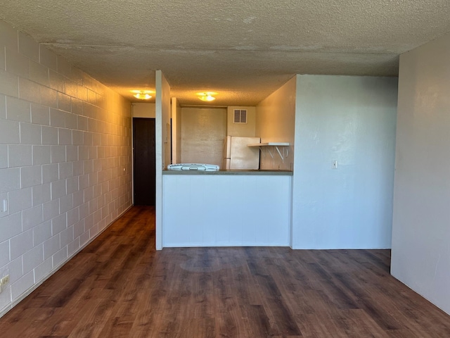 spare room with a textured ceiling and dark hardwood / wood-style floors