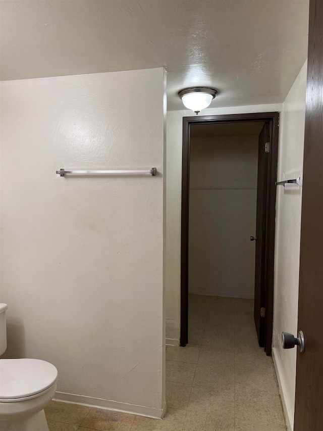 bathroom featuring tile flooring and toilet