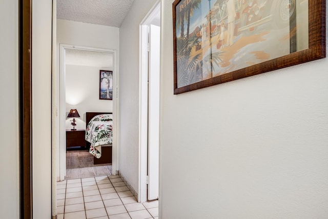 hallway with light tile patterned floors and a textured ceiling