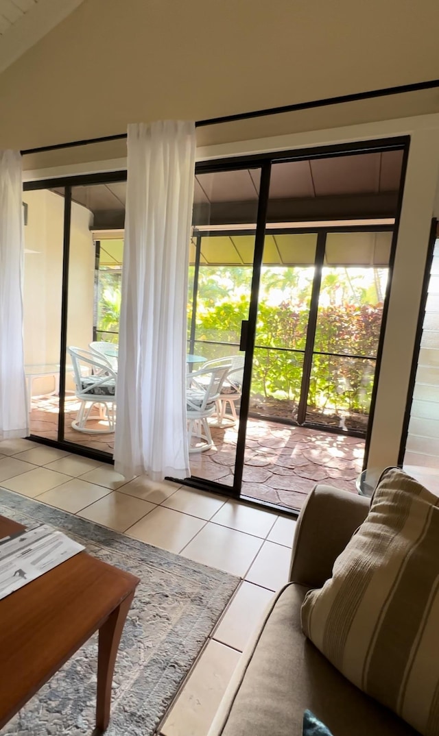 doorway featuring a wealth of natural light, light tile patterned flooring, and vaulted ceiling