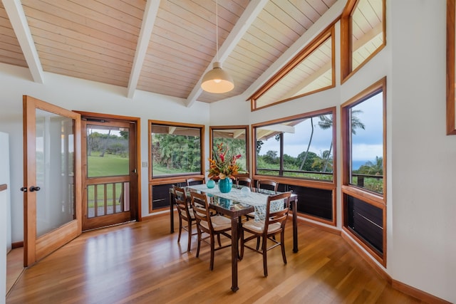 dining space with plenty of natural light, wood-type flooring, and vaulted ceiling with beams