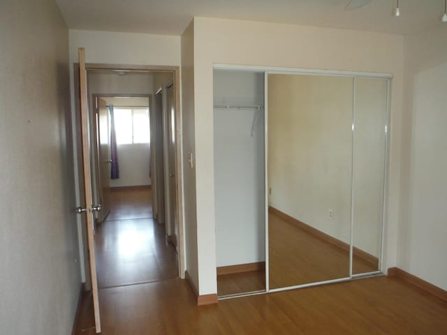 unfurnished bedroom featuring wood finished floors, baseboards, and a closet